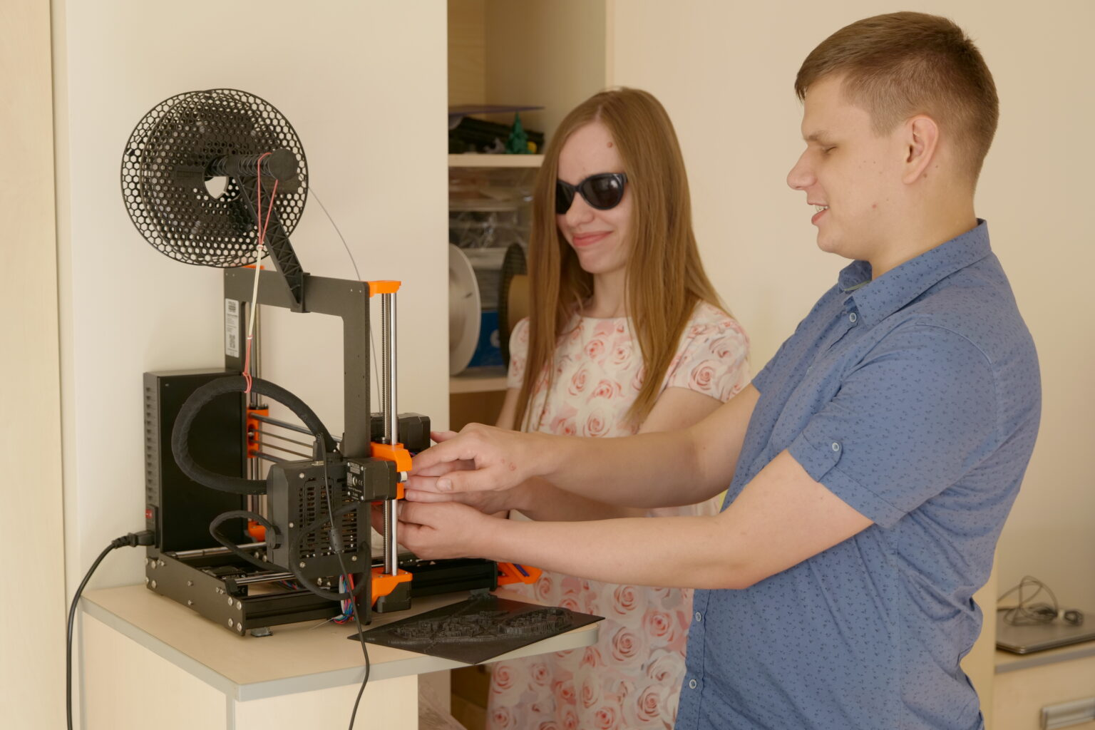 Dwoje młodych ludzi stoi przy drukarce 3D