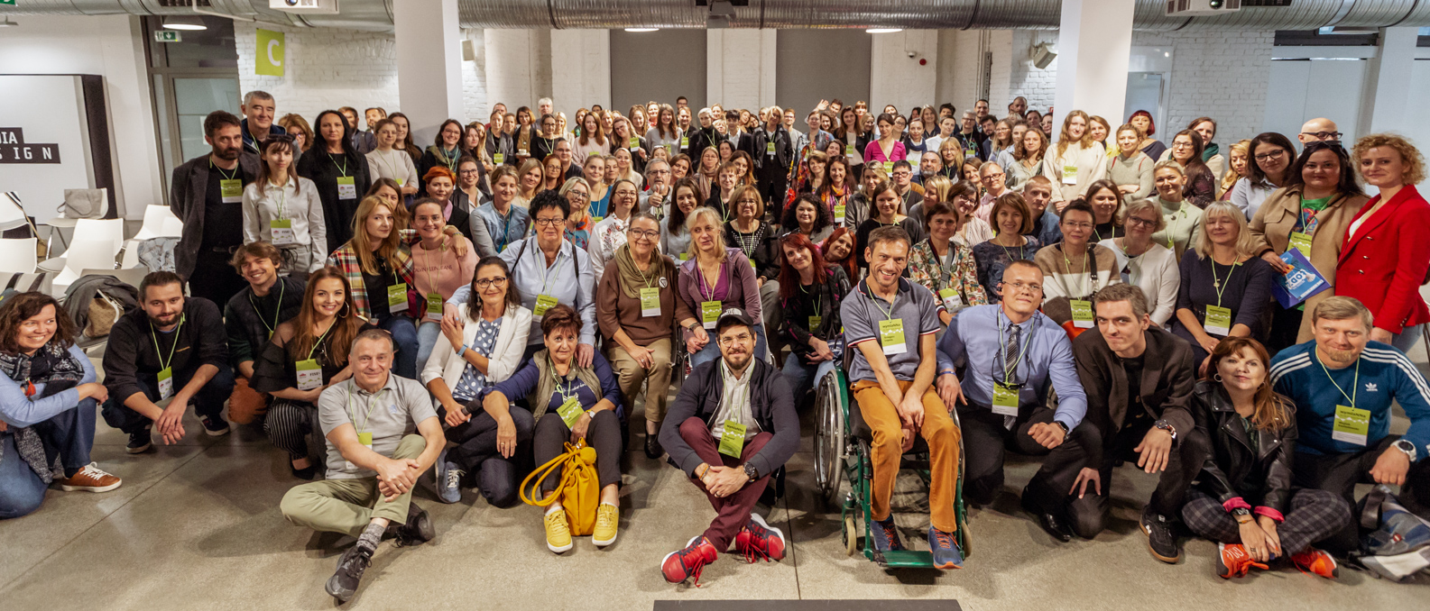 Zdjęcie grupowe przedstawiające ponad 100 osób stojących i siedzących - uczestników wydarzenia WymiaNNa z 2022 roku. Część osób się uśmiecha.