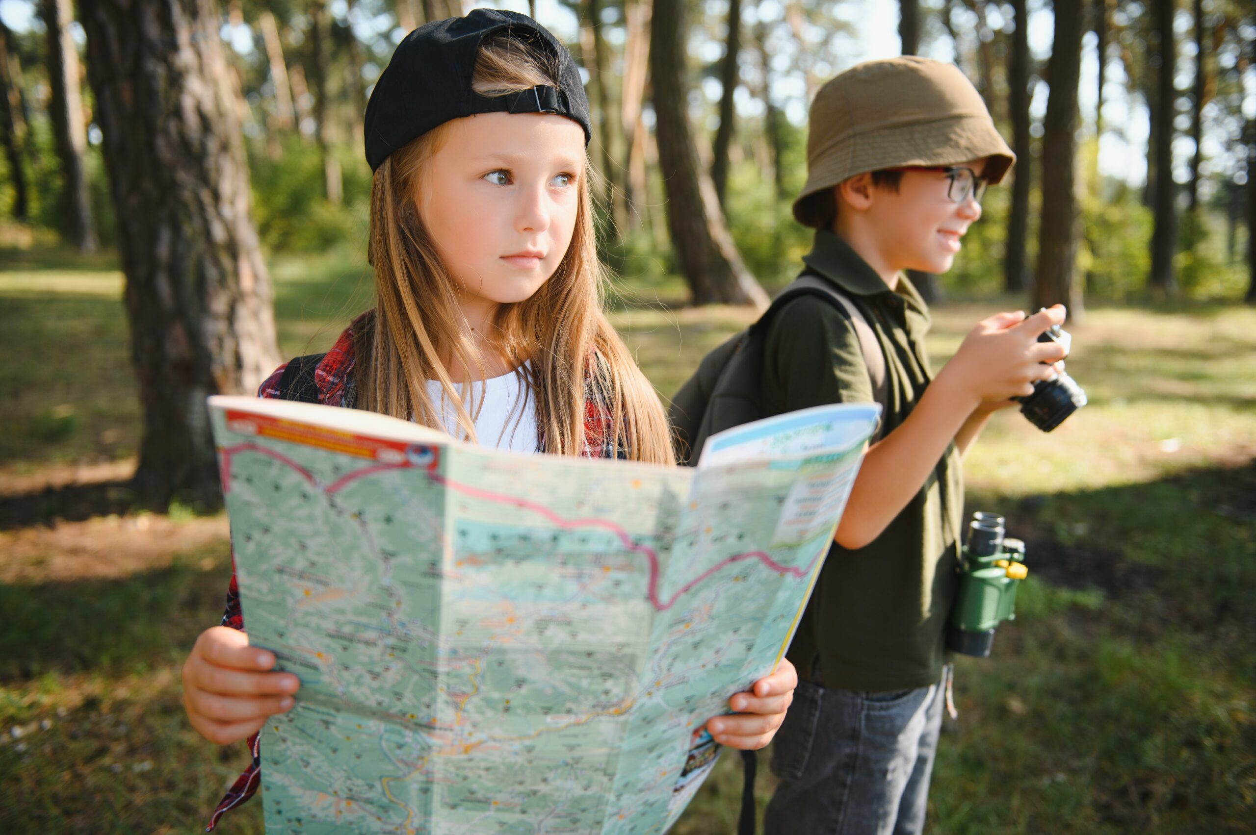 dzieci z mapą i lornetką w lesie