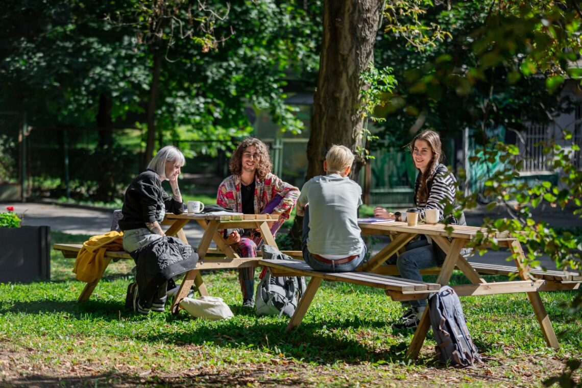 cztery młode osoby siedzące przy stole z ławkami na świeżym w parku