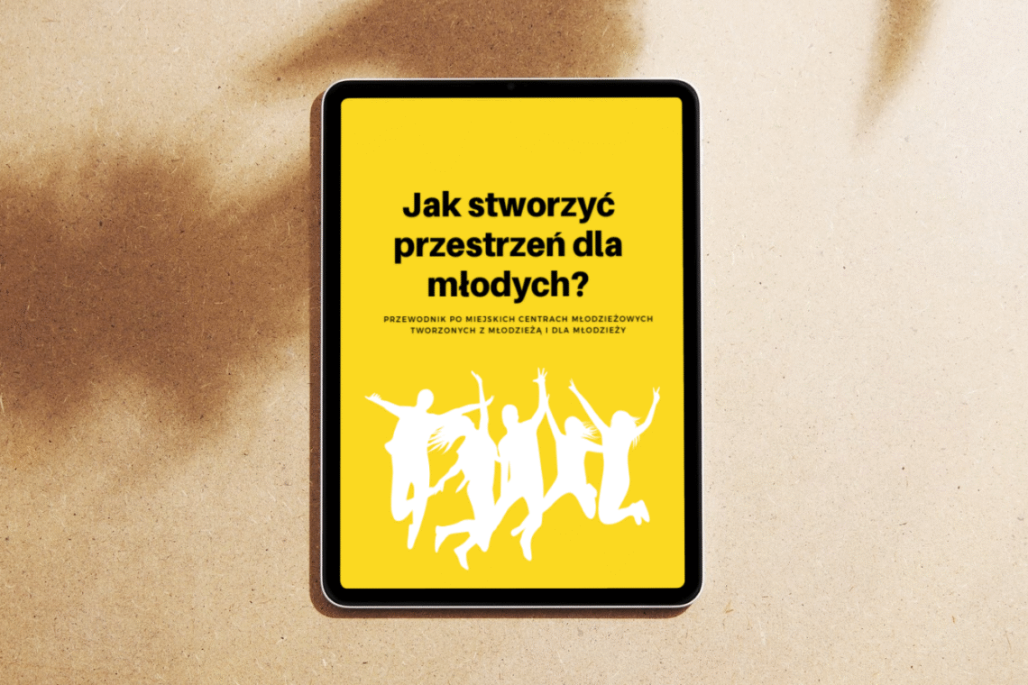 Na grafice znajduje się ipad, na którym została wyświetlona okładka publikacji "Jak stworzyć przestrzeń dla młodych?" Czarne litery na żółtym tle, poniżej napisu białe kontury podskakujących ludzi z podniesionymi rękami