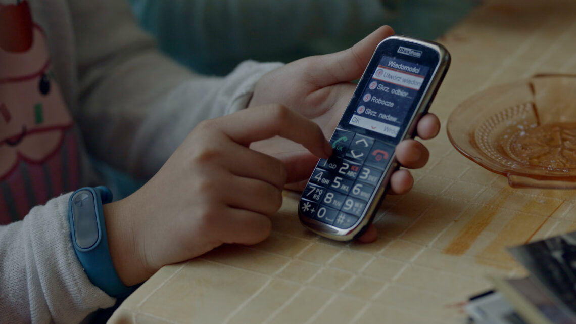 Dziewczynka pokazuje funkcje telefonu komórkowego.