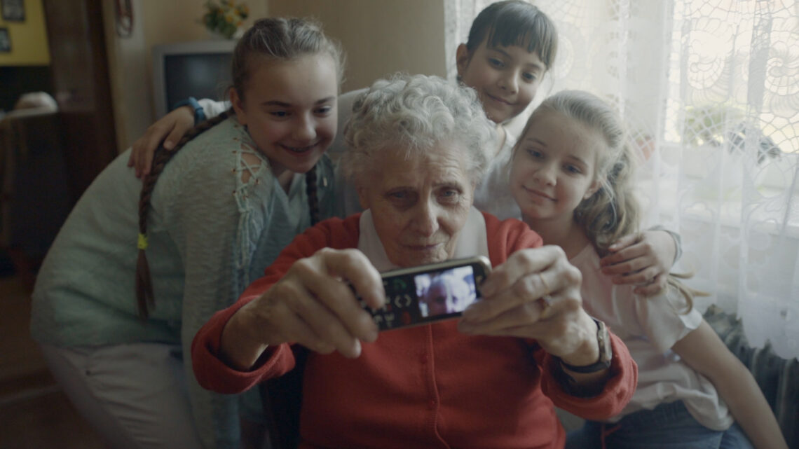 Seniorka robi sobie zdjęcie z trzema dziewczynkami.