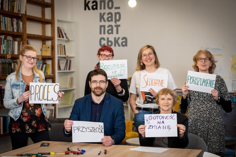 Grupa ludzi podczas warsztatów z kartkami z różnymi napisami, np "Porozumienie"