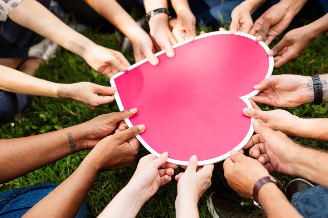 Wiele dłoni trzymających papierowe serce