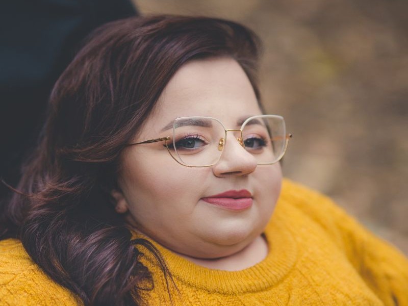 uśmiechnięta młoda kobieta w okularach patrząca w prosto w kamerę