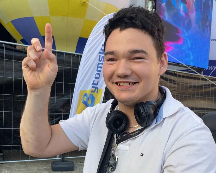 młody, uśmiechnięty mężczyzna pokazujący znak "V"