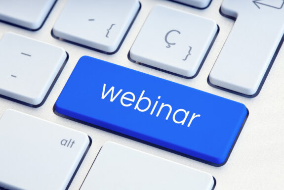 biała klawiatura, zbliżenie na niebieski klawisz z napisem "webinar"