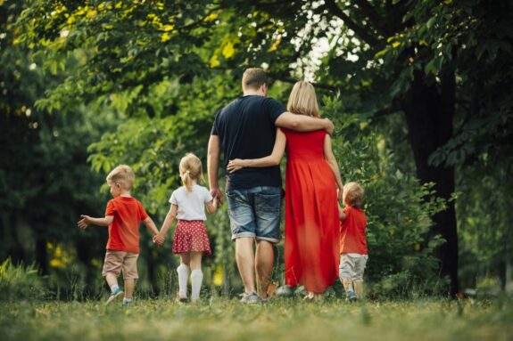 Zdjęcie rodziny tyłem, na zdjęciu rodzice i troje dzieci, idą trzymając się za ręce