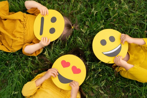 Dzieci z wyciętymi z papieru emotkami