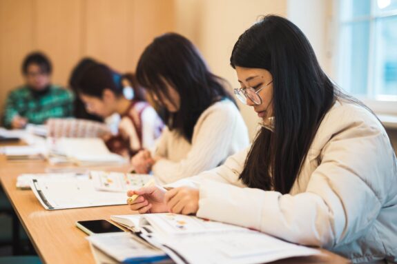 studentki w sali wykładowej nad książkami