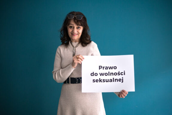 na niebieskim tle starsza kobieta trzymająca planszę z napisem "prawo do wolności seksualnej"