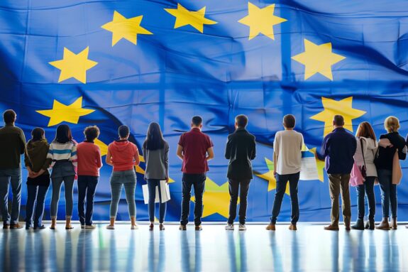 Ludzie stojący przed flagą Unii europejskiej